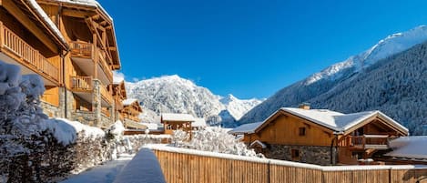 A snow-covered mountain village with wooden buildings and a clear blue sky.