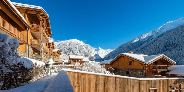 A snow-covered mountain village with wooden buildings and a clear blue sky.