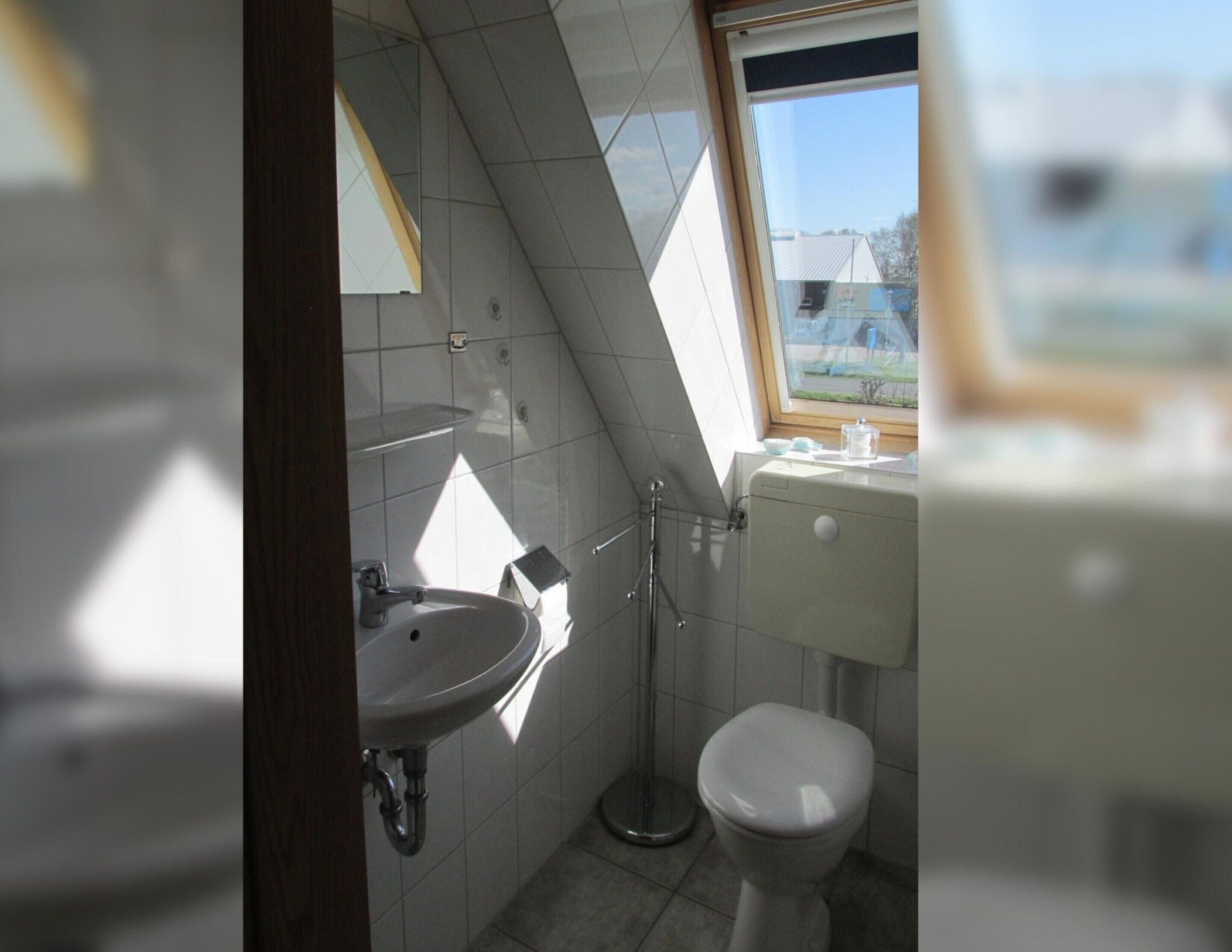Un bagno piccolo con lavandino, WC e finestra.