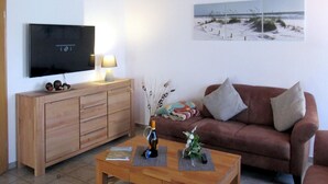 En stue med et træskab, et fjernsyn, en sofa og et sofabord.