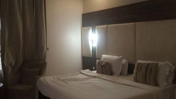 Una habitación de hotel con una cama grande, una silla y una mesita de noche.
