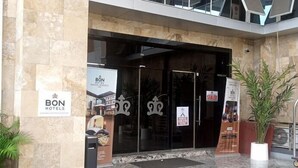 La entrada de un hotel con fachada de vidrio, un letrero de BON Hotels y un letrero en la puerta que dice 'SEALLED'.