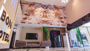 Un vestíbulo de hotel con un mural grande en la pared, un área de descanso y una recepción.