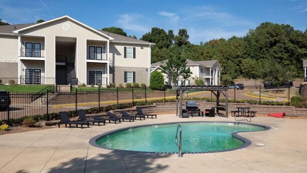 A pool area with lounge chairs and a covered seating area, surrounded by a fence. - Newly remodeled 2-bedroom condo in Oxford!  (Oxford)