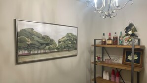 Ein Essbereich mit einem Gemälde, einer Kristallleuchter und einer Vitrine mit Flaschen und Gläsern.
