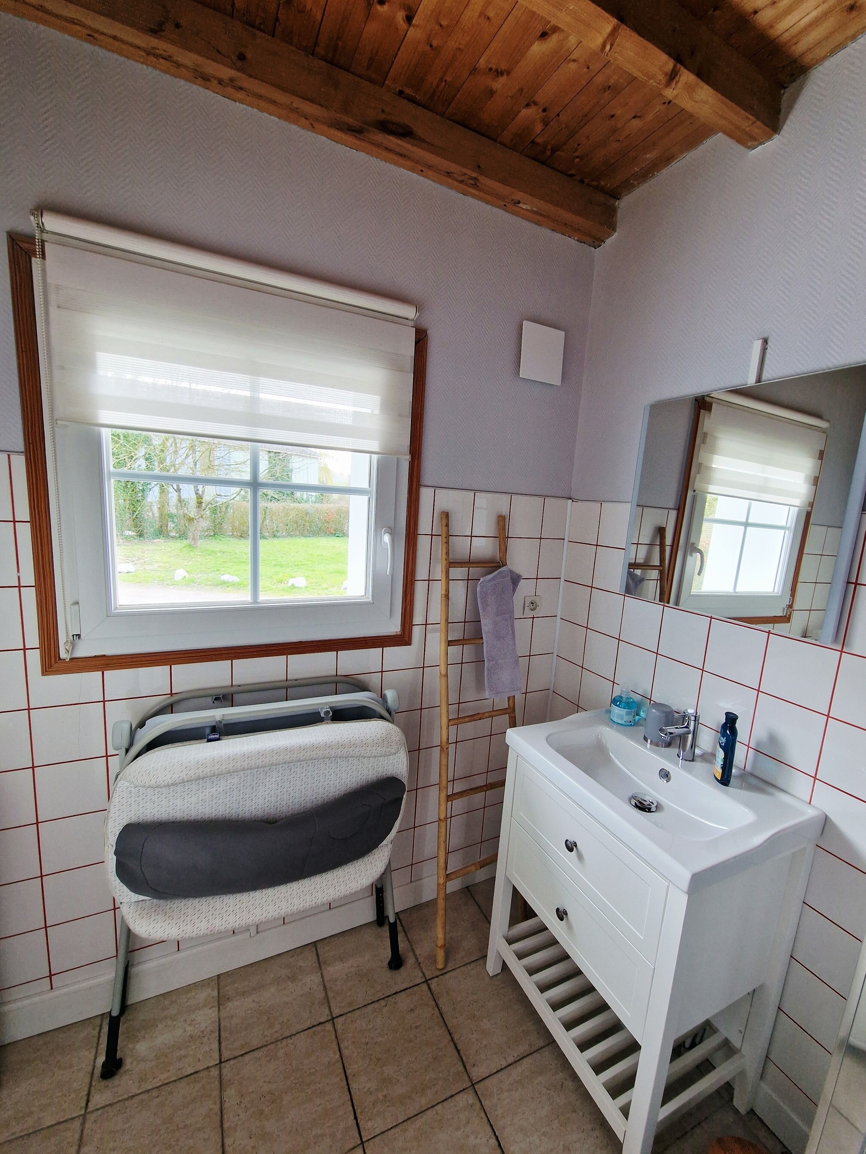 A bathroom with a bathtub, a sink, a window, and a mirror.