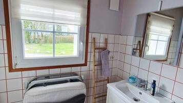 A bathroom with a bathtub, a sink, a window, and a mirror.