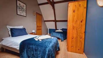Un dormitorio con dos camas, vigas de madera, un armario de madera y un cuadro en la pared.