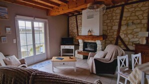 A cozy living room with a stone fireplace, a television, and a large window. - L'Etable, gîte between land and sea.  (Verlincthun)
