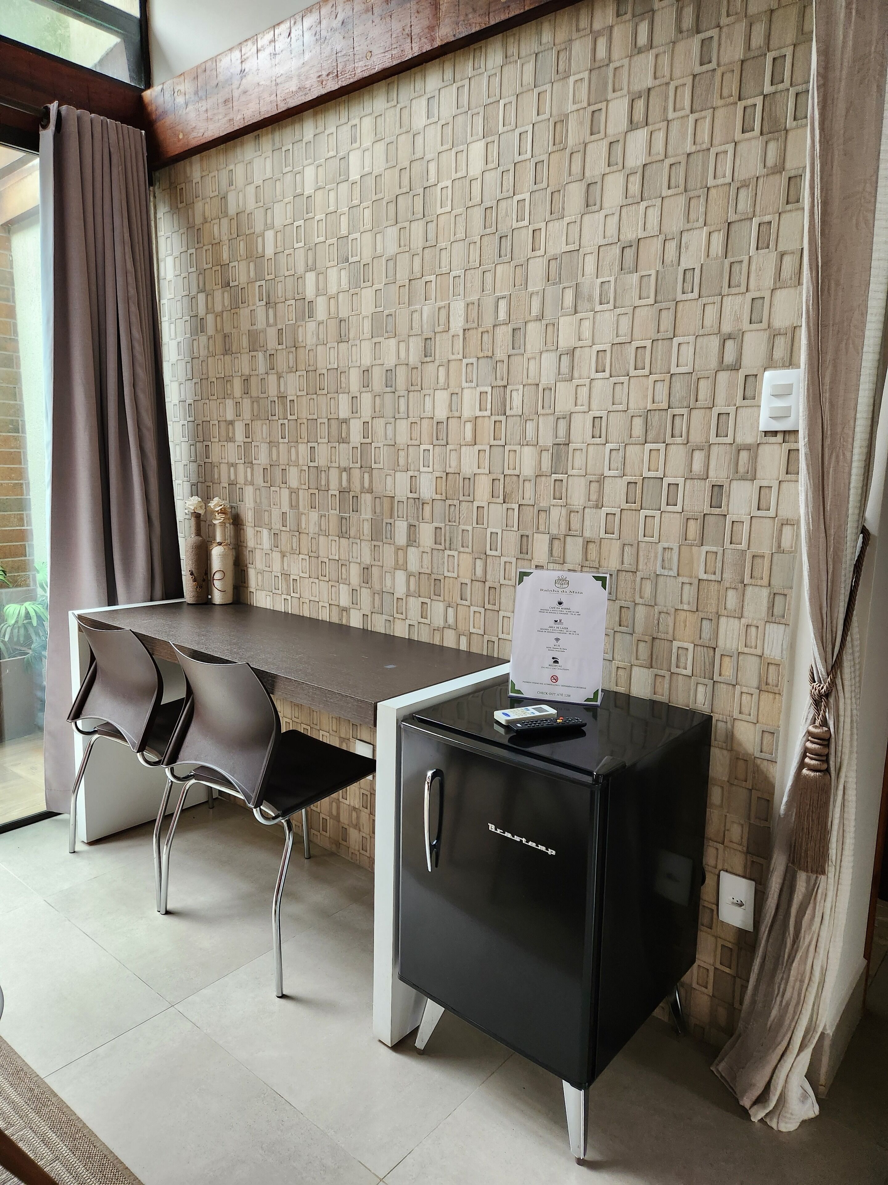 A modern room with a dining table, chairs, a minibar, and a patterned wall.