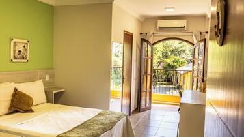 Ein Hotelzimmer mit Bett, Nachttisch, Fenster und offener Tür, die auf einen Balkon führt.
