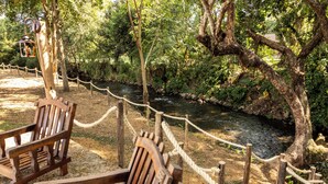 Un banc en bois au bord d’une rivière, séparé par une barrière faite de cordes.