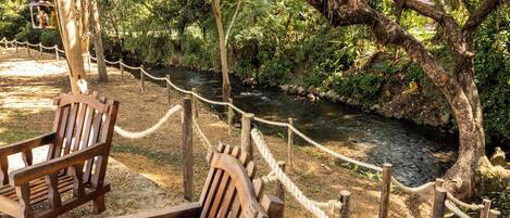 A wooden bench by a river with a rope barrier.