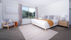 Een slaapkamer met een groot bed, een nachtkastje, een stoel en een raam met uitzicht.