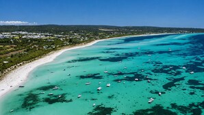 Vue aérienne d’une zone côtière avec une plage, des bateaux et une zone résidentielle.