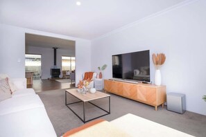 Een moderne woonkamer met een bank, salontafel, televisie en een open haard.