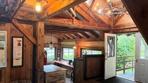 Een rustiek houten interieur met zichtbare balken, een bar en een uitzicht door een deur naar buiten.