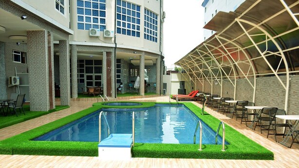 Una piscina interior con zona de borde de piscina, rodeada por un edificio con ventanas grandes y un área de estar cubierta.