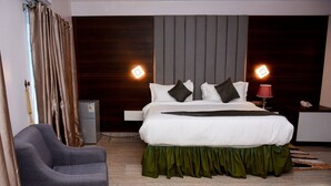 Una habitación de hotel moderna con una cama grande, un escritorio, una silla y un armario.