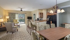 A spacious living area with a dining table, chairs, a sofa, and a television.