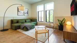 A modern living room with a green sofa, a round coffee table, and a floor lamp. - HOMA-Comfort&Style-1BR-Spacious-Natural Light-FeelHome-A/C-SelfCheckIn-Metro (Montréal)