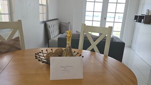 Een ronde houten eettafel met een fles champagne en een welkomstkaart.