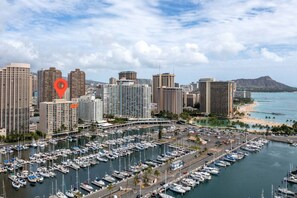 A marina with numerous boats docked, surrounded by high-rise buildings and a beach in the background.