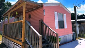A pink mobile home with a wooden porch and a small staircase leading to the entrance. - 2 bedrooms, 3 beds, 2 bathrooms cozy house by the bay. (Bacliff)
