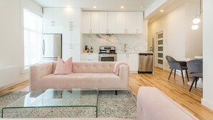 Una sala moderna con un sofá, una mesa de centro de vidrio y un comedor con sillas.