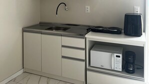 Een compacte keuken met een ingebouwde magnetron, koffiezetapparaat en een kleine koelkast.