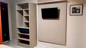 Een slaapkamer met een bed, een inbouwkast, een flatscreen televisie en een lijst met een afbeelding aan de muur.