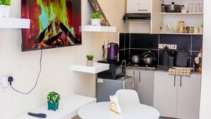 A modern kitchen with a flat-screen TV, a coffee maker, a kettle, and a stove.
