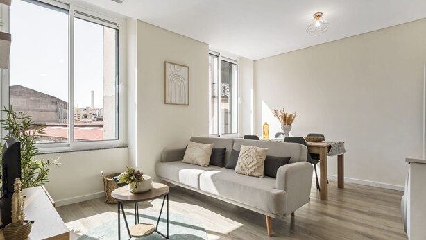 A modern living room with a sofa, a coffee table, and a dining area with a table and chairs. - Carmo Charm Apartment by Homie (Funchal)