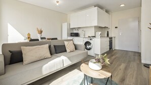 Un appartement moderne comprenant un espace de vie, une kitchenette et un coin buanderie.