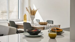 Une table à manger avec un bol de céréales, un verre de jus de fruits et une assiette avec des fruits.