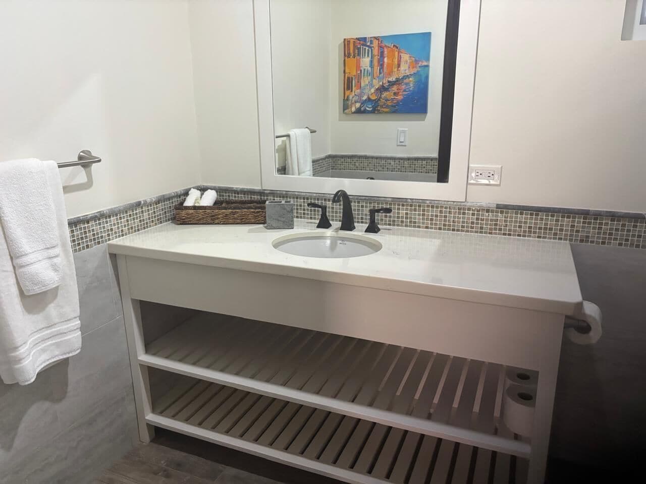 A bathroom with a white vanity, a sink, a mirror, and a tiled backsplash.