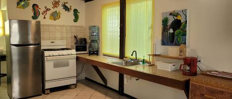 A kitchen with a refrigerator, stove, sink, and a water dispenser.