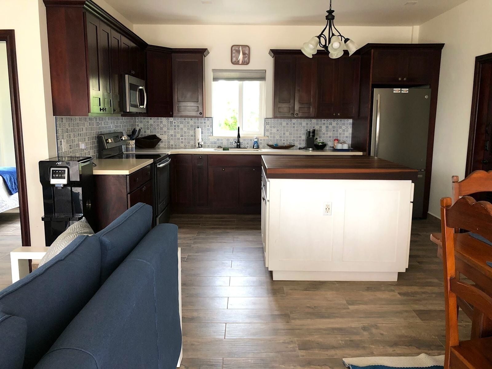 Una cocina moderna con armarios de madera oscura, una isla central, un microondas integrado y un dispensador de agua.