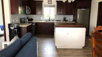 Una cocina moderna con armarios de madera oscura, una isla central, un microondas integrado y un dispensador de agua.