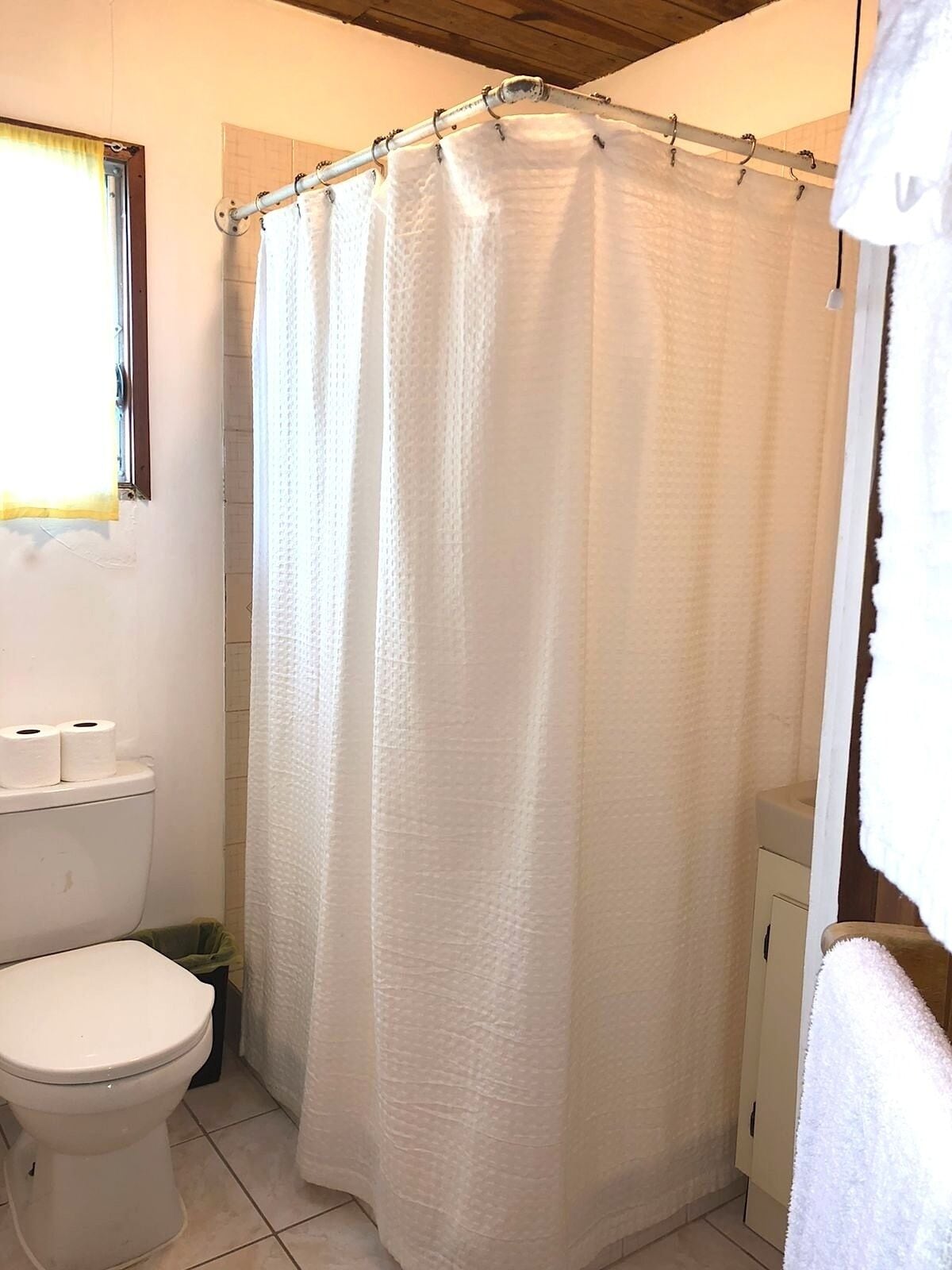 Un baño con cortina de ducha blanca, un inodoro y un lavabo.