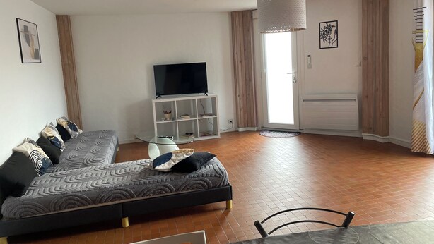 A modern living room with a sofa, a TV on a stand, a glass coffee table, and a dining area with a table and chairs. - F3 with terrace and secure parking (Châteaugay)