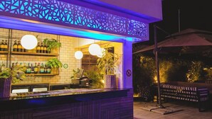 An outdoor bar area with a counter, shelves of bottles, and hanging lights. - Asabana Suites and Hotels Ltd (Asaba)