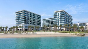 Ein Hotel direkt am Strand mit mehreren Hochhäusern, einem Sandstrand und Palmen.