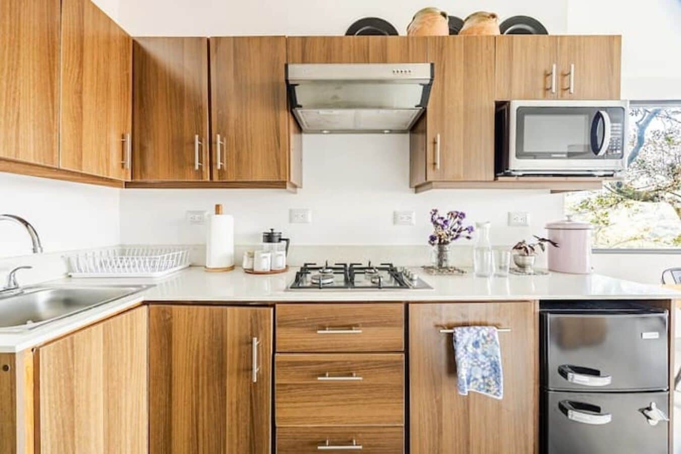 A kitchen with wooden cabinets, a gas stove, a microwave, and a refrigerator.