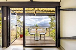 Ein Balkon mit Tisch, Stühlen, einem Blumentopf und Blick auf die Berge.