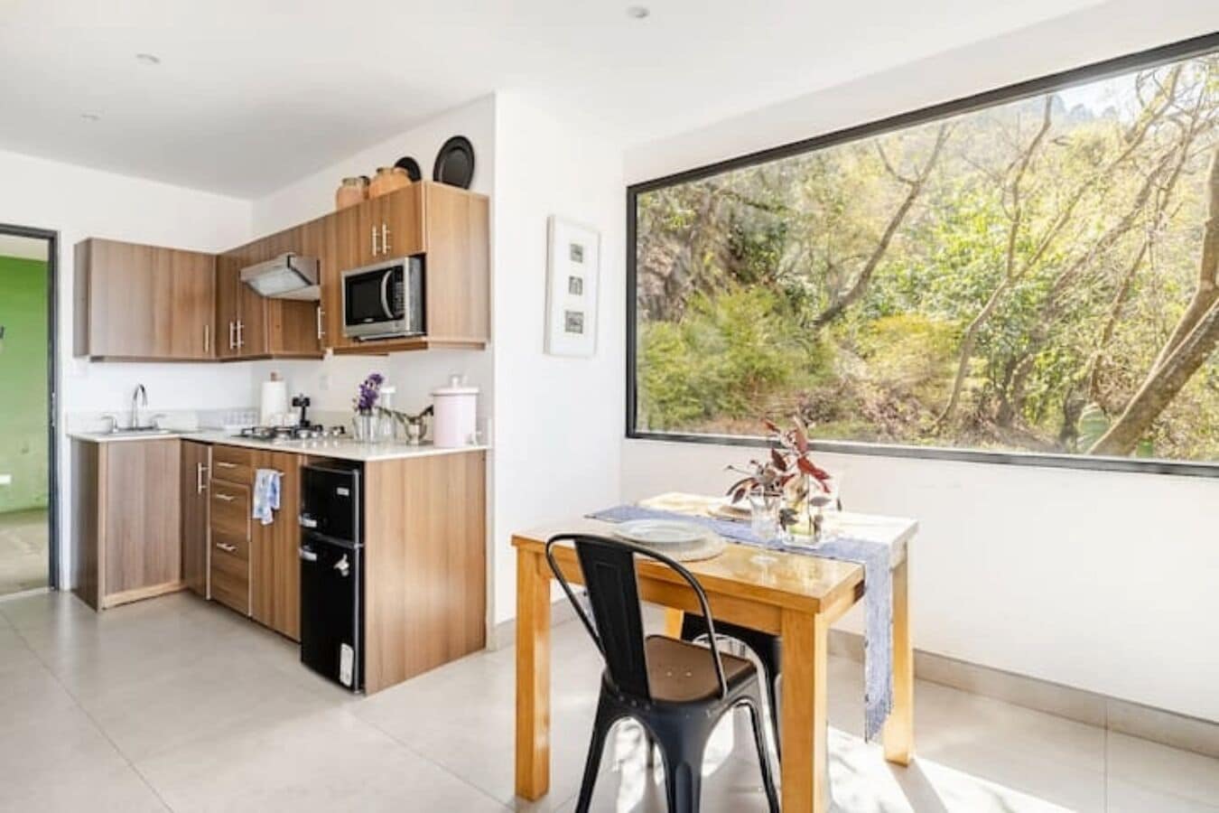 A modern kitchen with wooden cabinets, a microwave, and a dining area with a table and chairs.