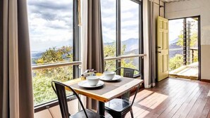 A dining area with a table set for two, large windows, and a view of the outdoors.