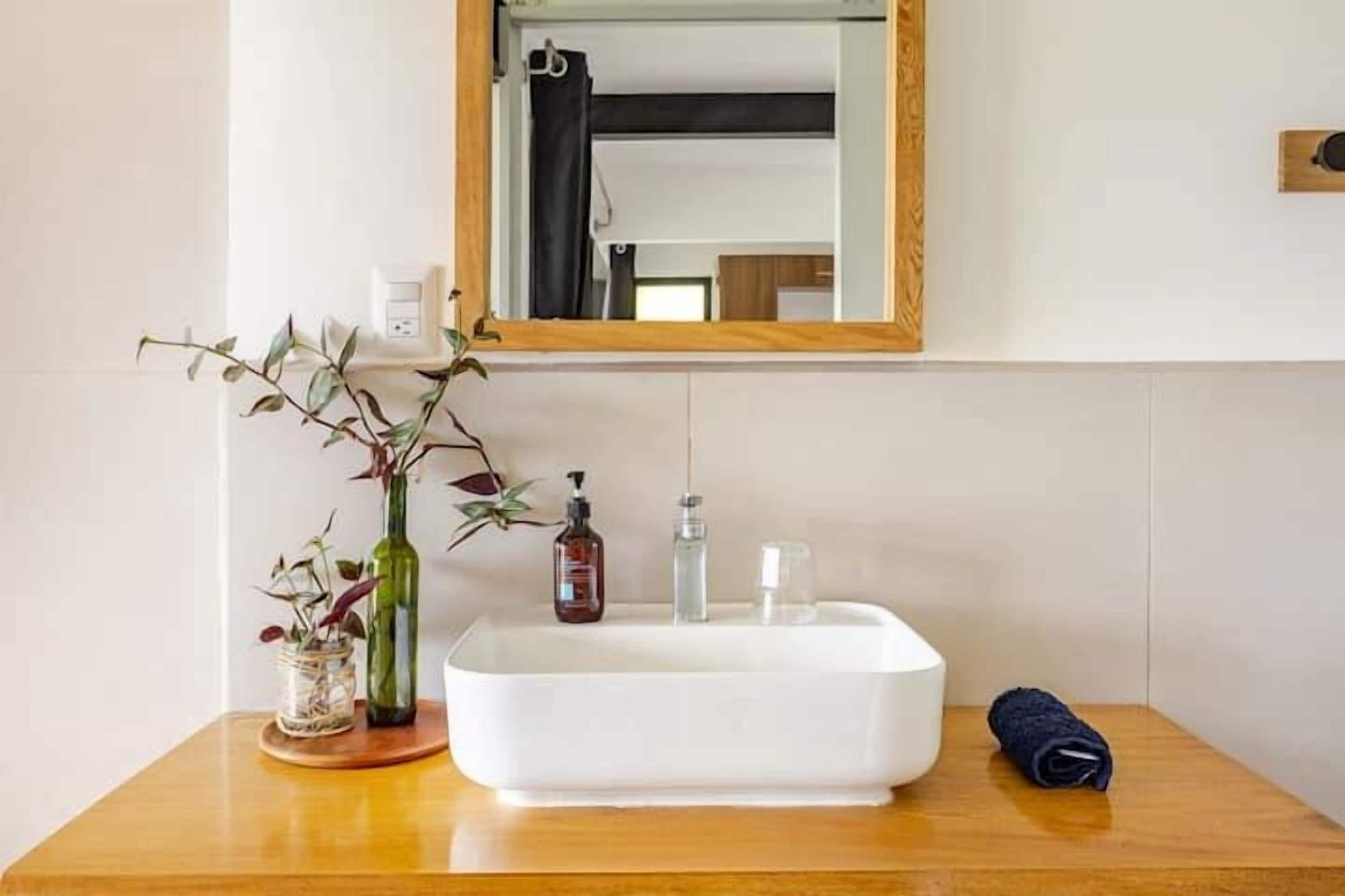 Een badkamer met een wit wastafel, een spiegel, een houten aanrechtblad en een handdoek.