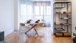 Uma sala de jantar moderna com uma mesa redonda, cadeiras e uma estante com livros e caixas.