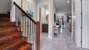 A spacious hallway with a wooden staircase, a kitchen area, and a dining space. - 948B - 4BR $700+ in freebies incl golf, Pool (Miramar Beach)